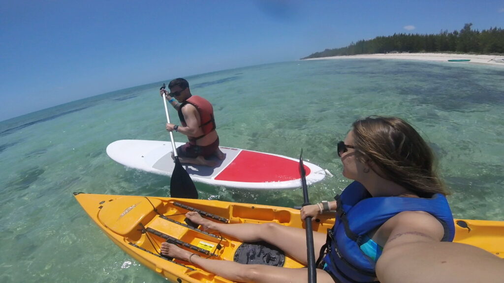 Sam on a kayak and Dylan on a paddle board off the shore of Fortuna Beach in Grand Bahama Island