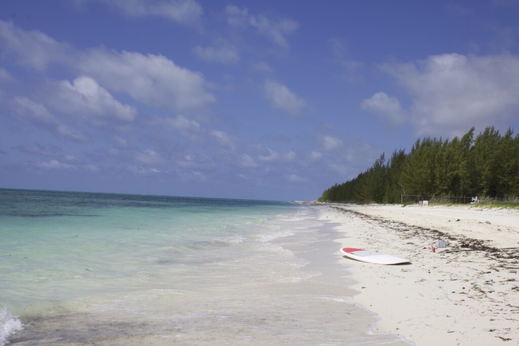 Picture of Fortuna Beach in Freeport, Grand Bahama with a pink and white paddle board on shore.